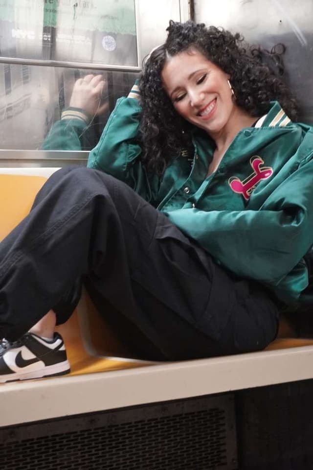 Ali reclined on a subway bench in a green satin jacket